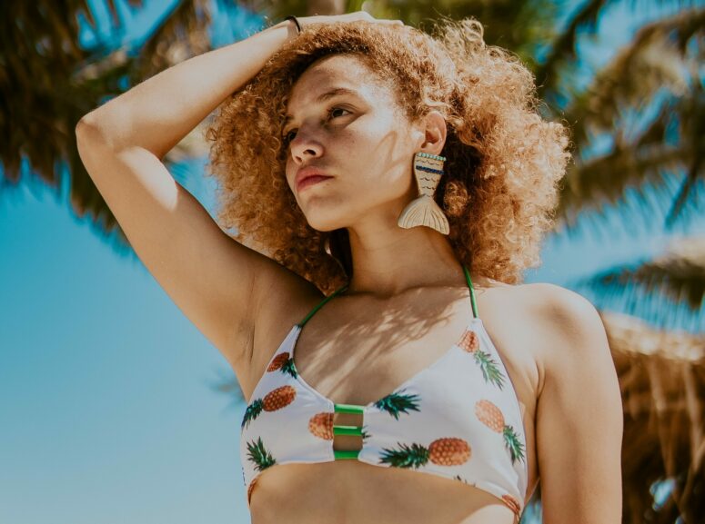 An image of a lady in summer clothing holding her hair