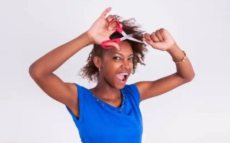 A person holding a pair of scissors and the ends of her hair