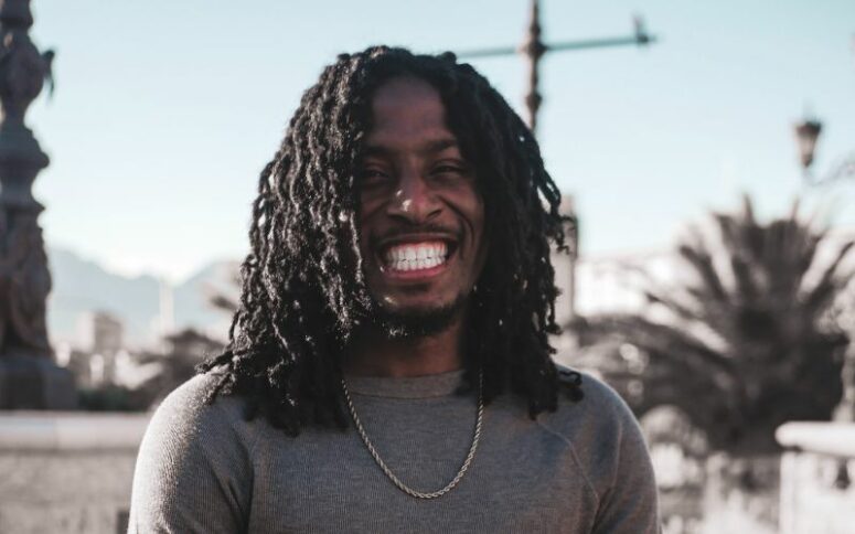 A person with black dreadlocks smiling